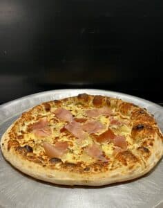 **Pizza blanche – A creamy delight topped with delicate slices of prosciutto and a hint of herbs at Pizza les 2 Frangins, Bompard – Marseille.**